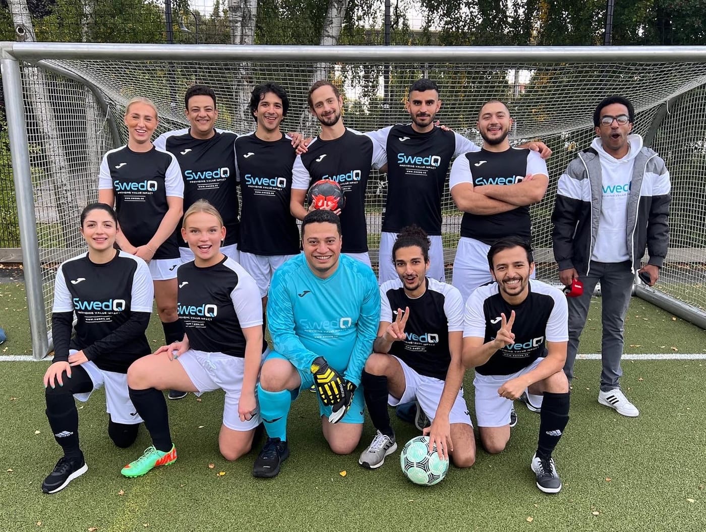 The SwedQ football team posing together on the pitch in club shirts