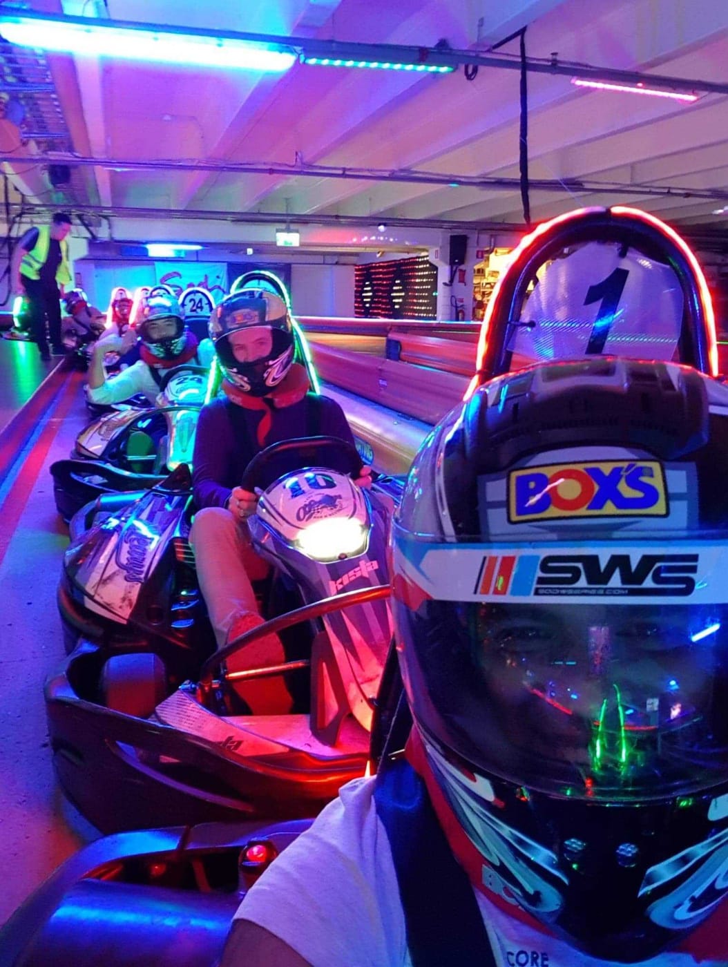 SwedQ colleagues in go-karts under neon lighting at an indoor track