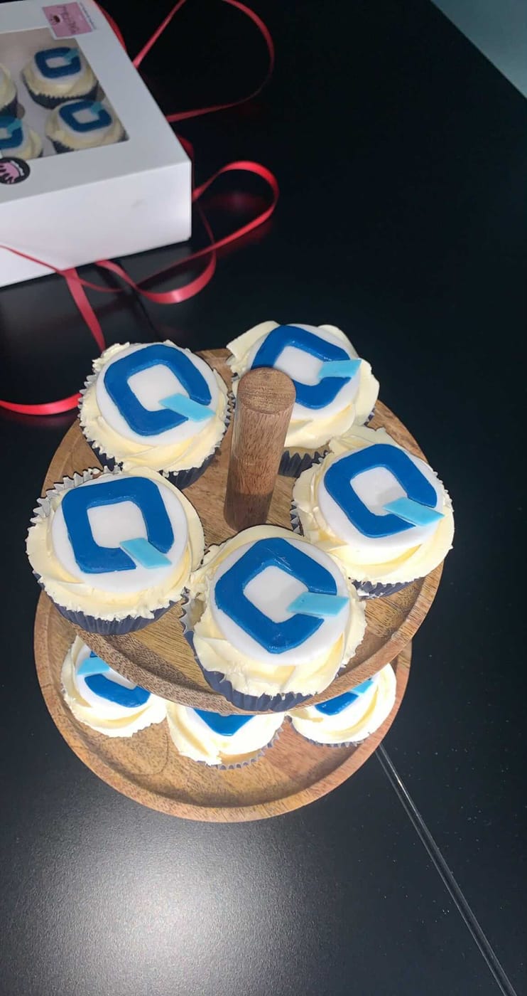 Cupcakes decorated with the SwedQ logo on a wooden board